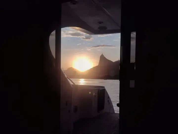 Pôr do sol com o Cristo Redentor visto de dentro de um iate
